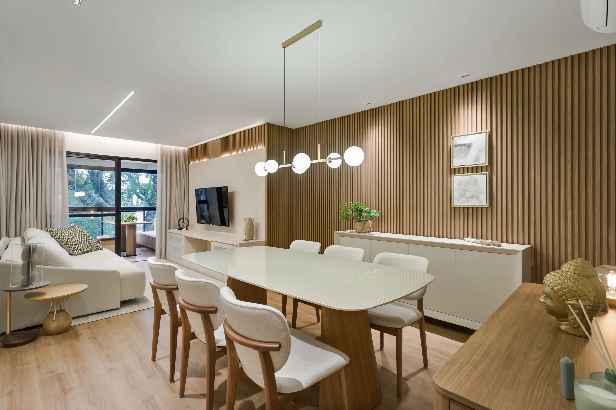 Sala integrada com mesa de jantar, painel ripado de madeira e sofá claro