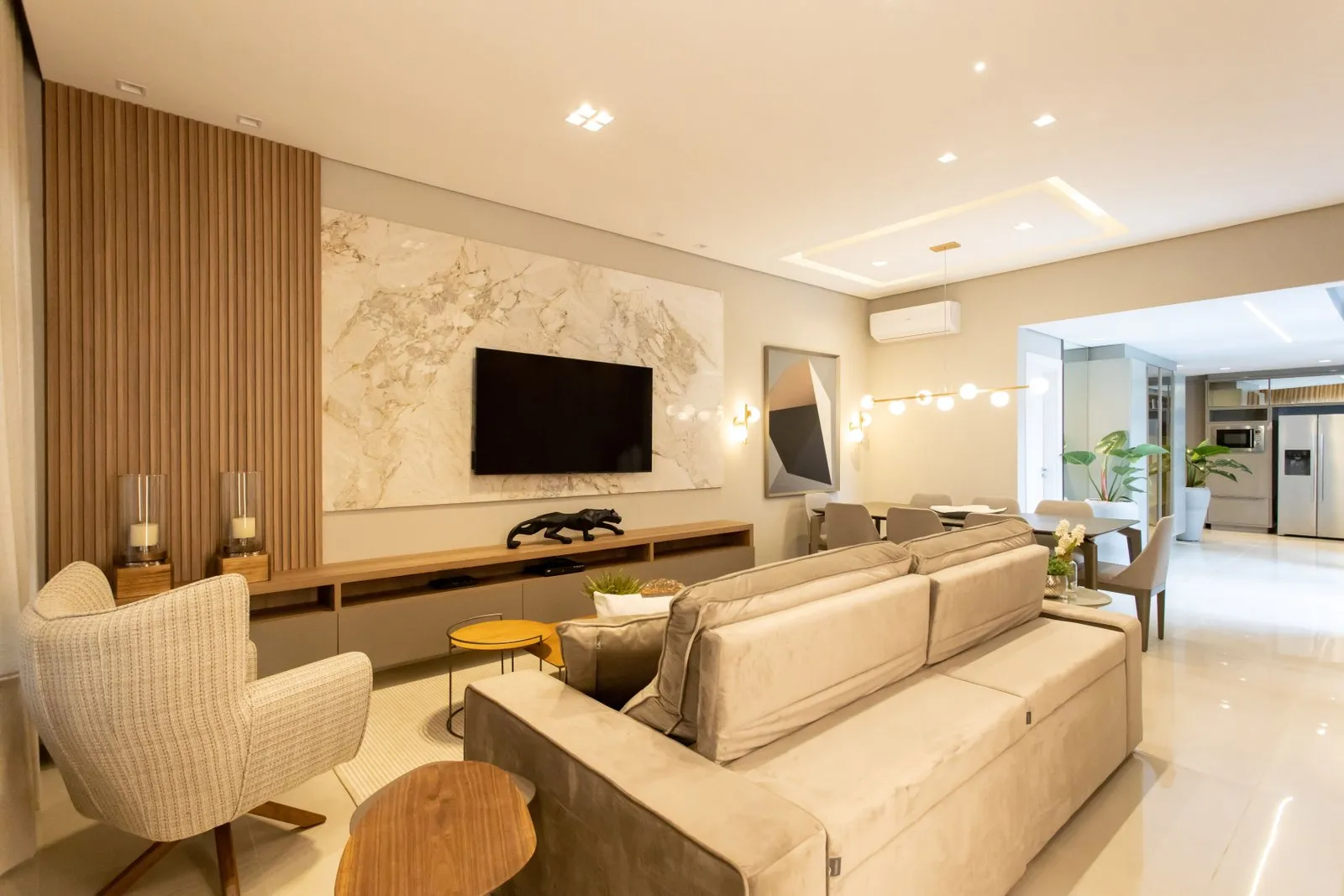 Sala de estar com painel de mármore, ripado e sofá bege
