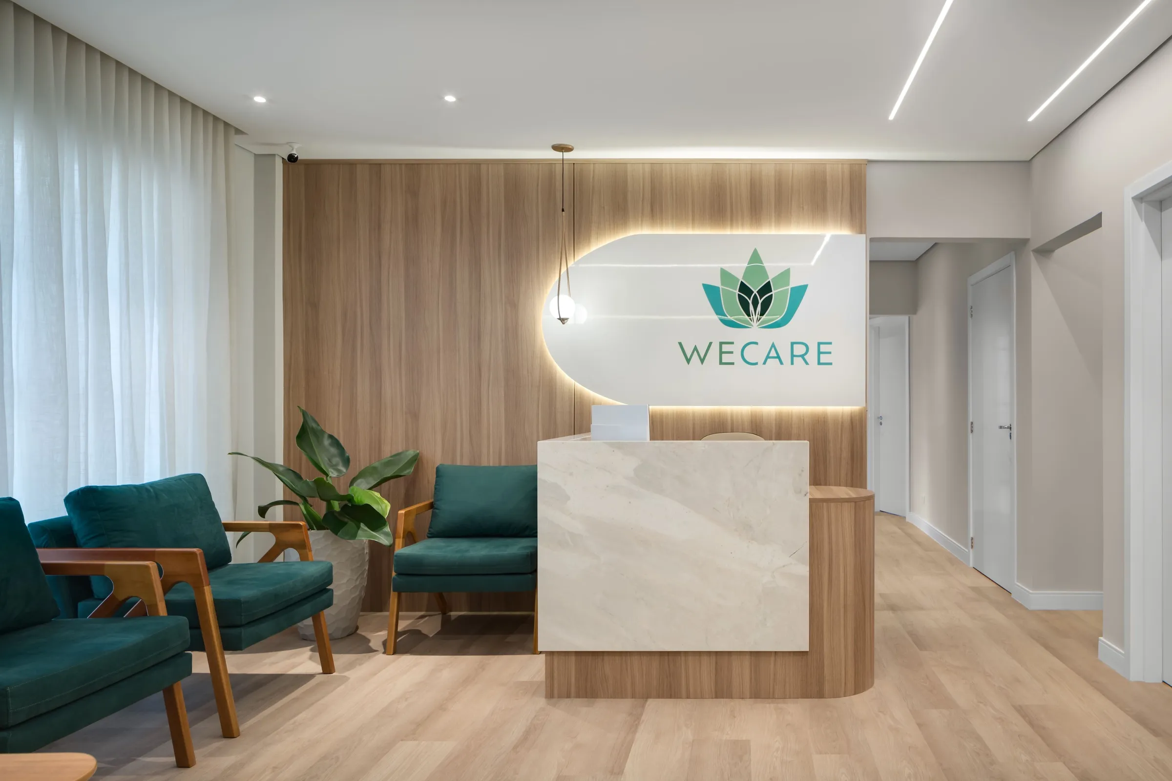 Recepção com balcão de mármore, painel de madeira e poltronas verdes