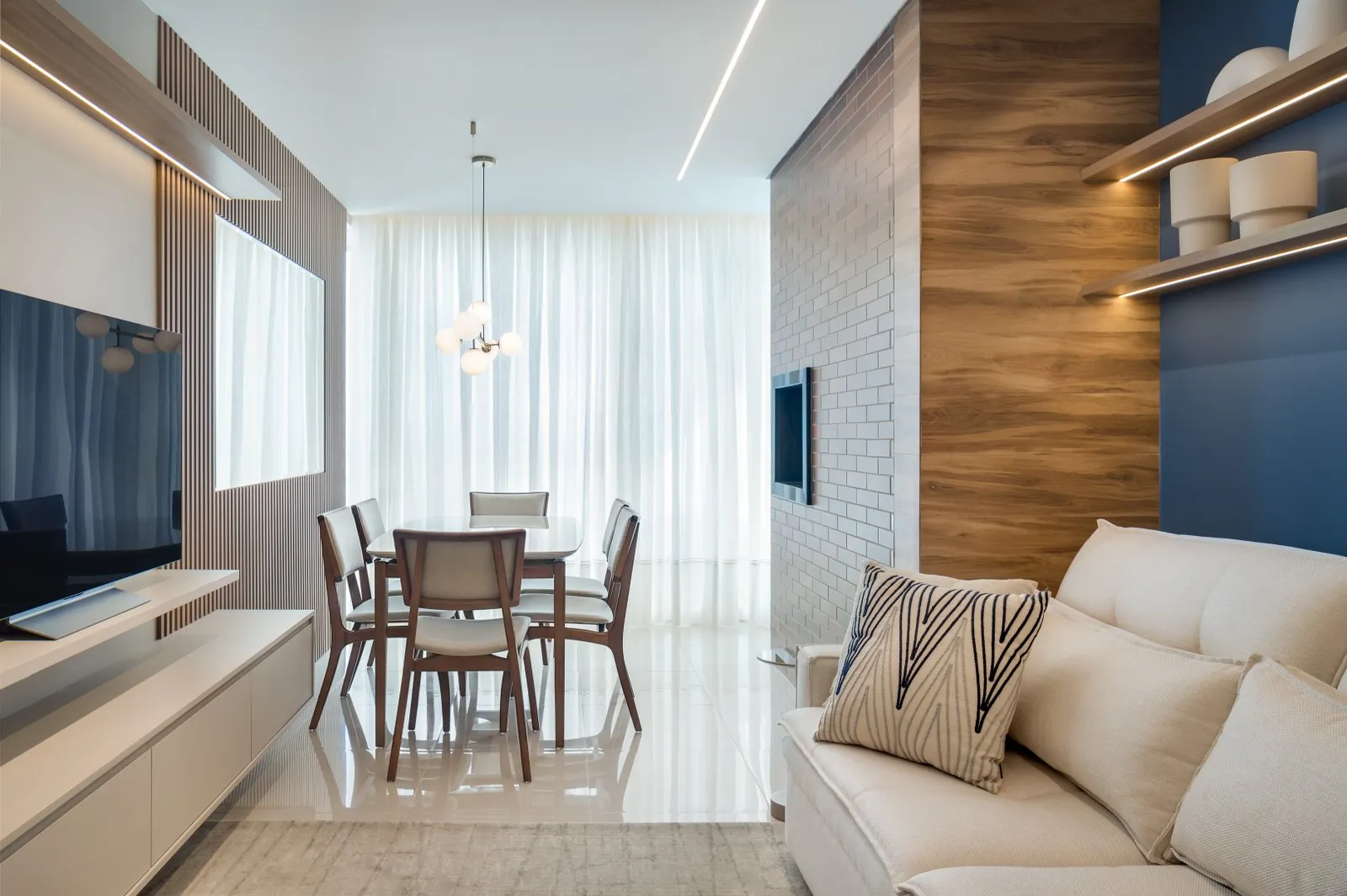 Sala com painel ripado, mesa de jantar ao fundo e cortina de voil