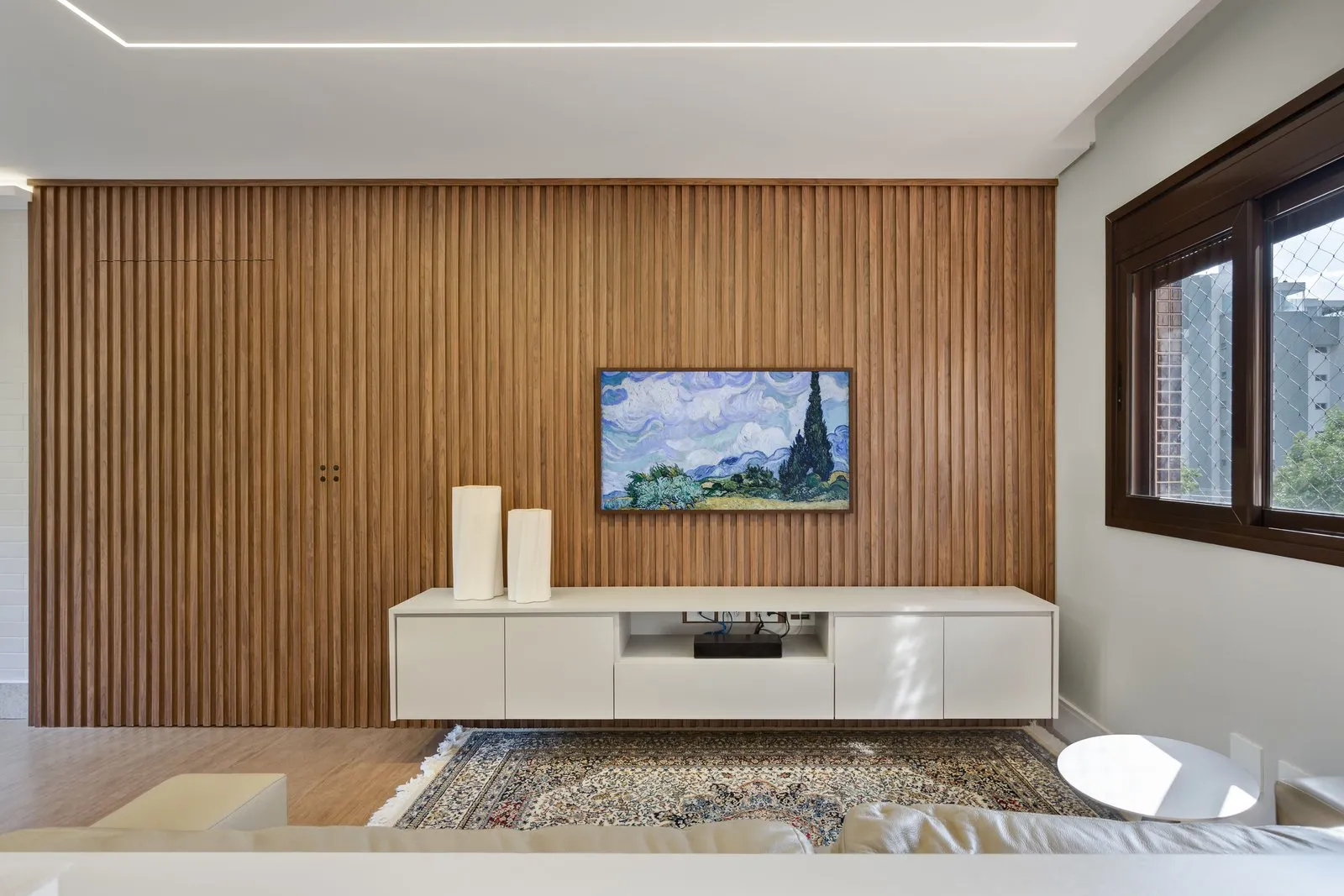 Painel ripado de madeira com rack branco suspenso e TV