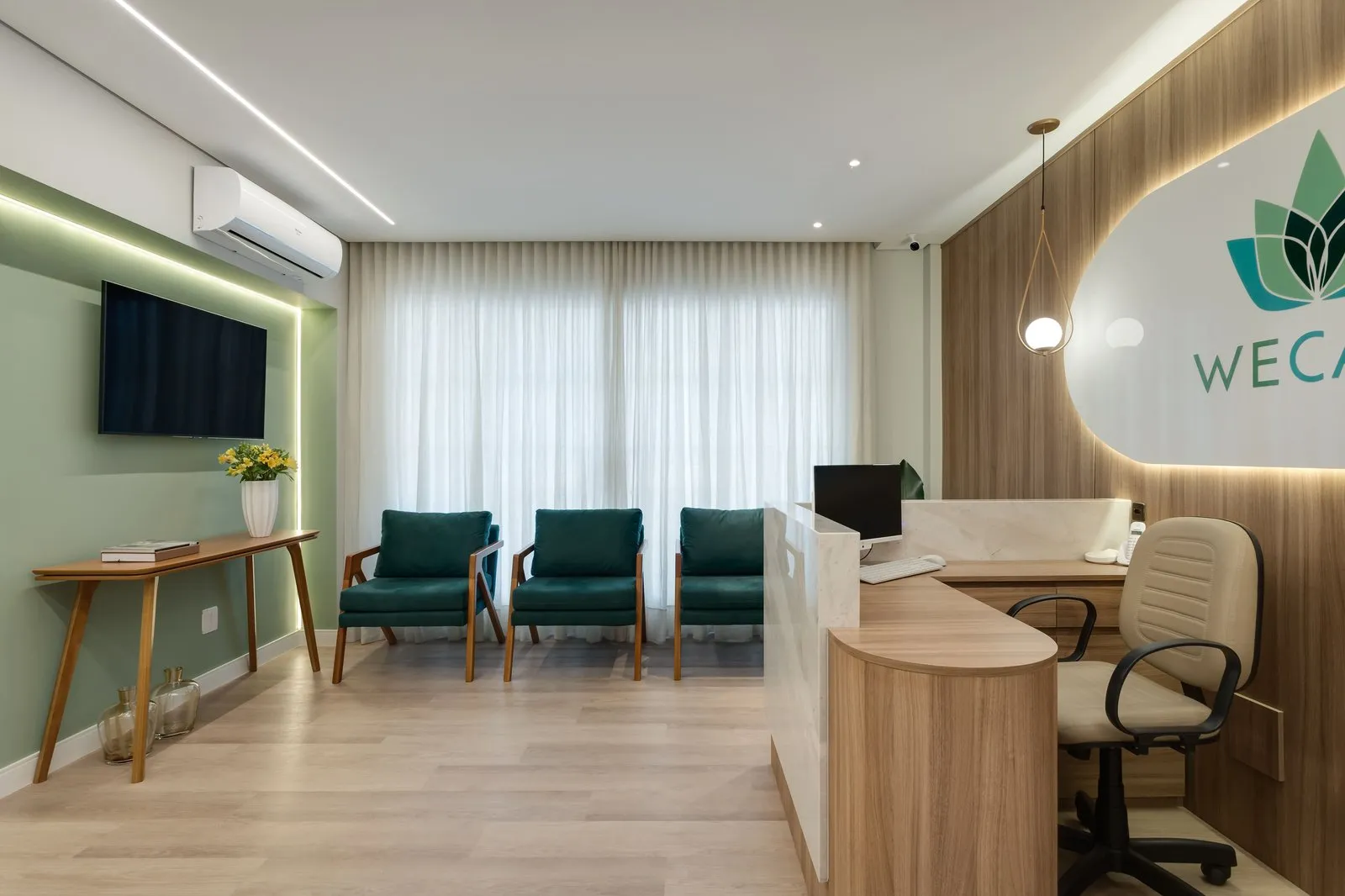 Sala de espera com poltronas verdes, cortina de linho e parede verde-sálvia