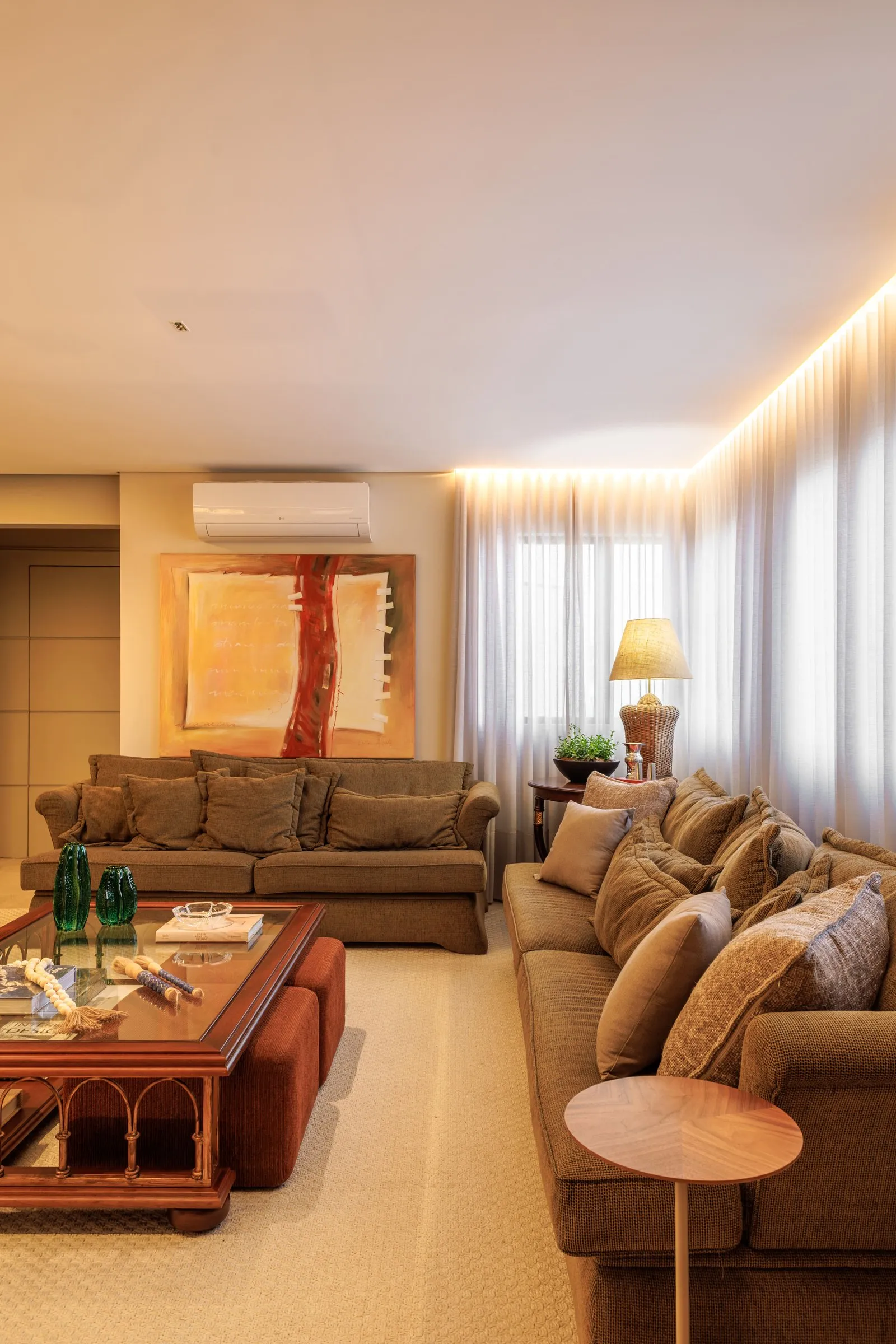 Sala de estar com sofás, mesa de centro de vidro e cortina com luz embutida