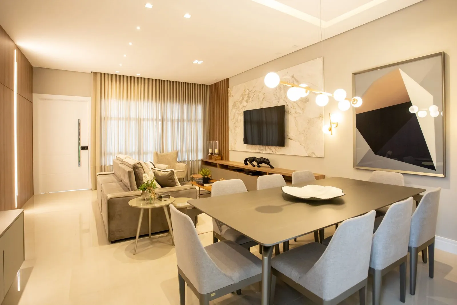 Sala de jantar integrada à sala com mesa escura e pendente de globos