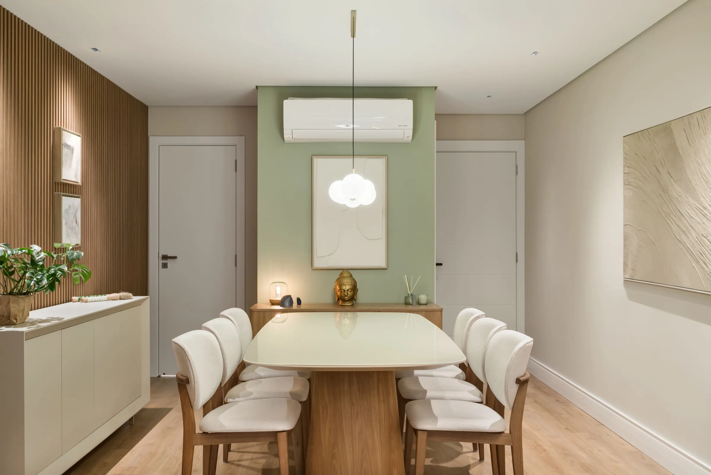 Sala de jantar com mesa clara, cadeiras estofadas e parede verde