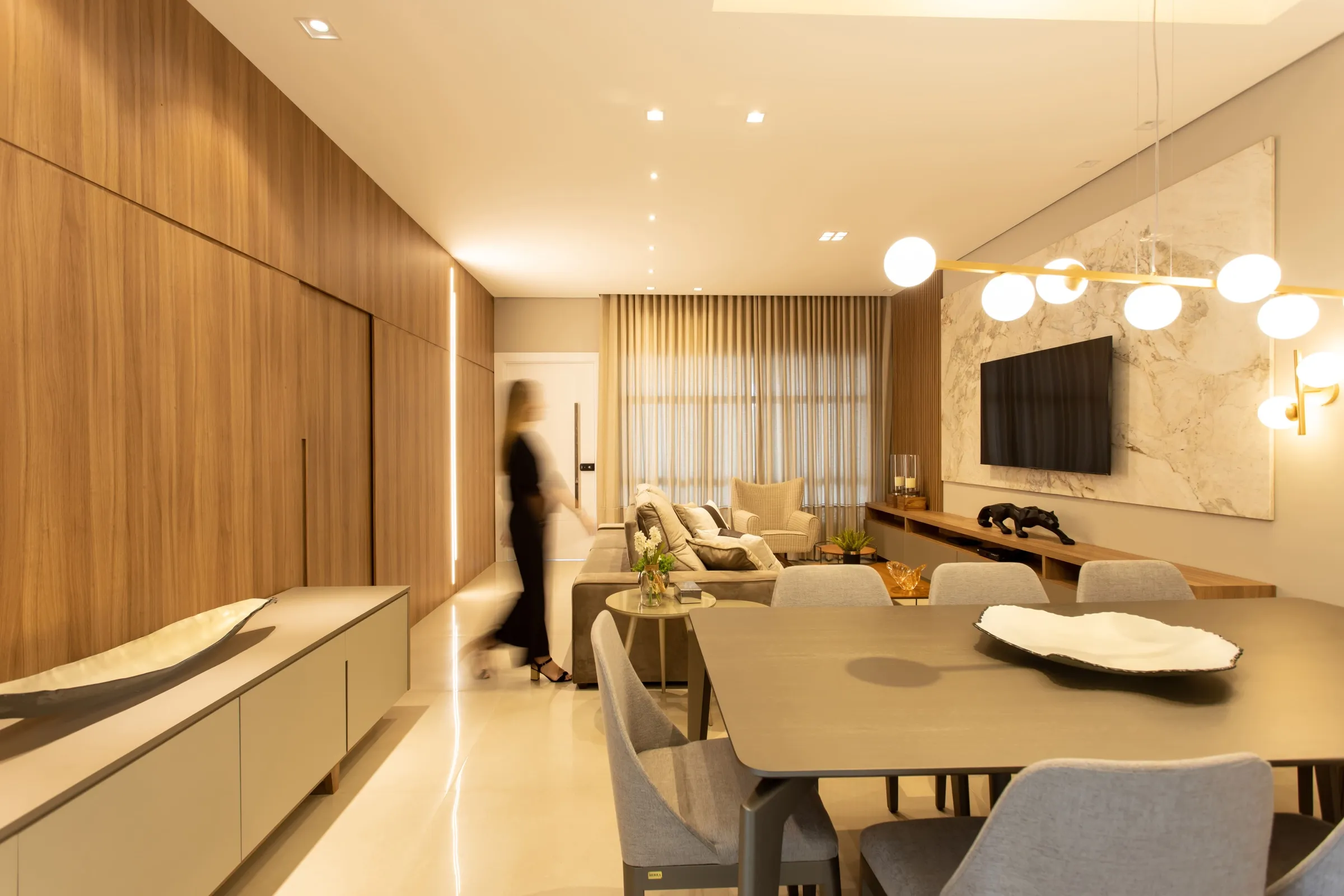 Sala e jantar em corredor com painel de madeira e pessoa passando