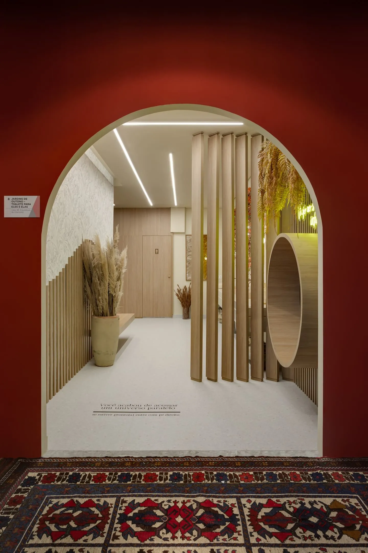 Arco vermelho com vista para toalete em madeira e ripado