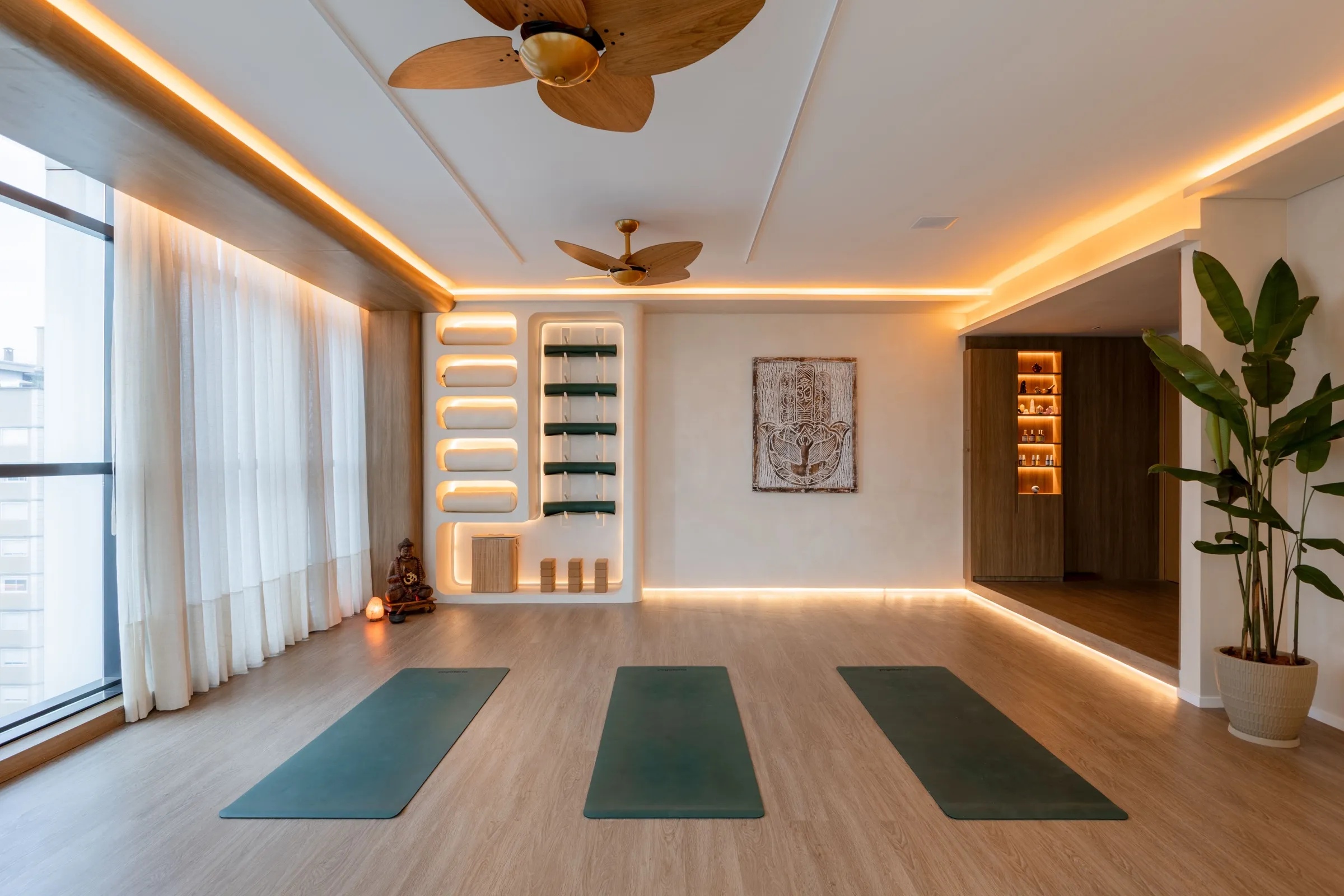Sala de yoga ampla com sanca de luz, ventiladores e estante curva ao fundo