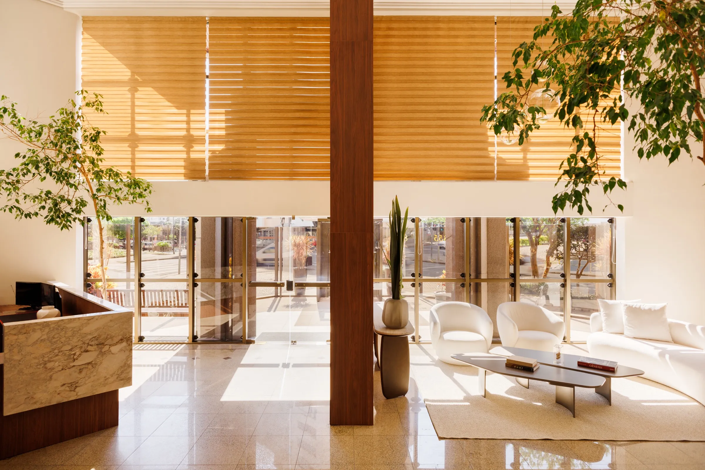 Hall amplo com pé-direito duplo, pilar de madeira e recepção em mármore