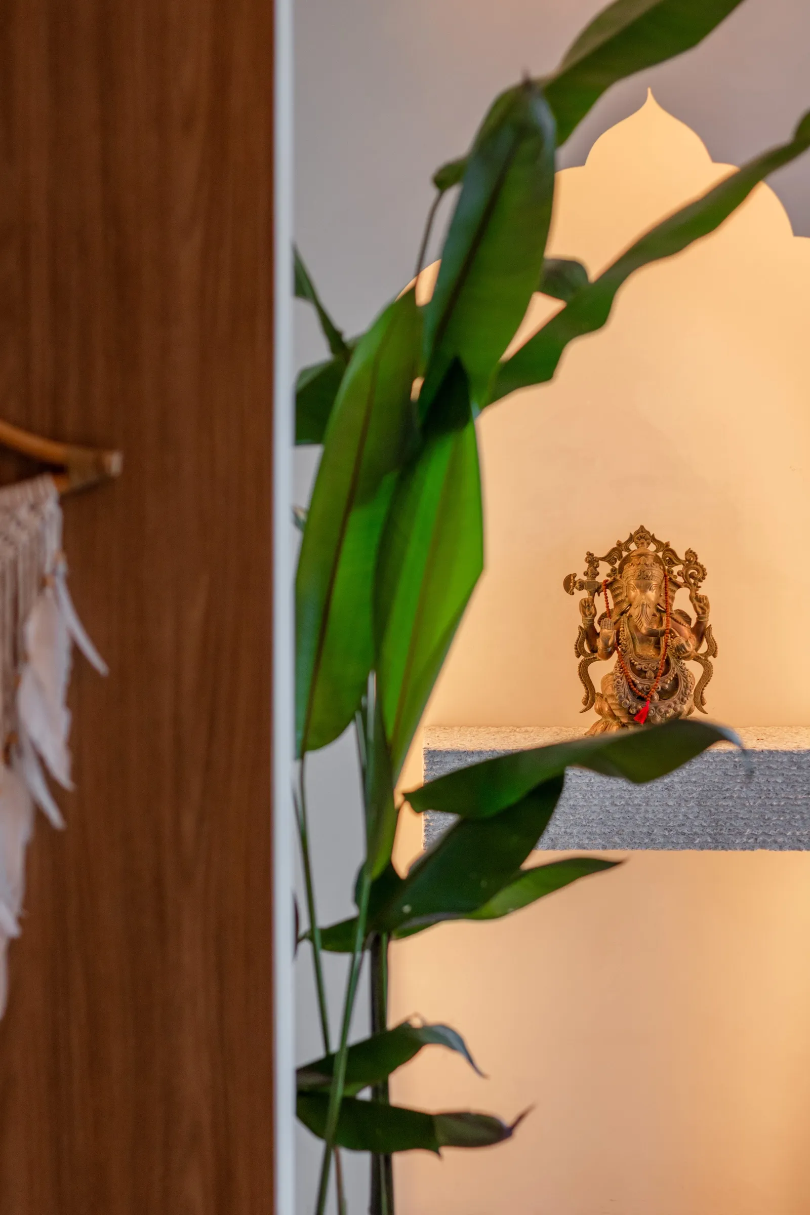 Estátua de Ganesha em nicho iluminado atrás de folhas de planta