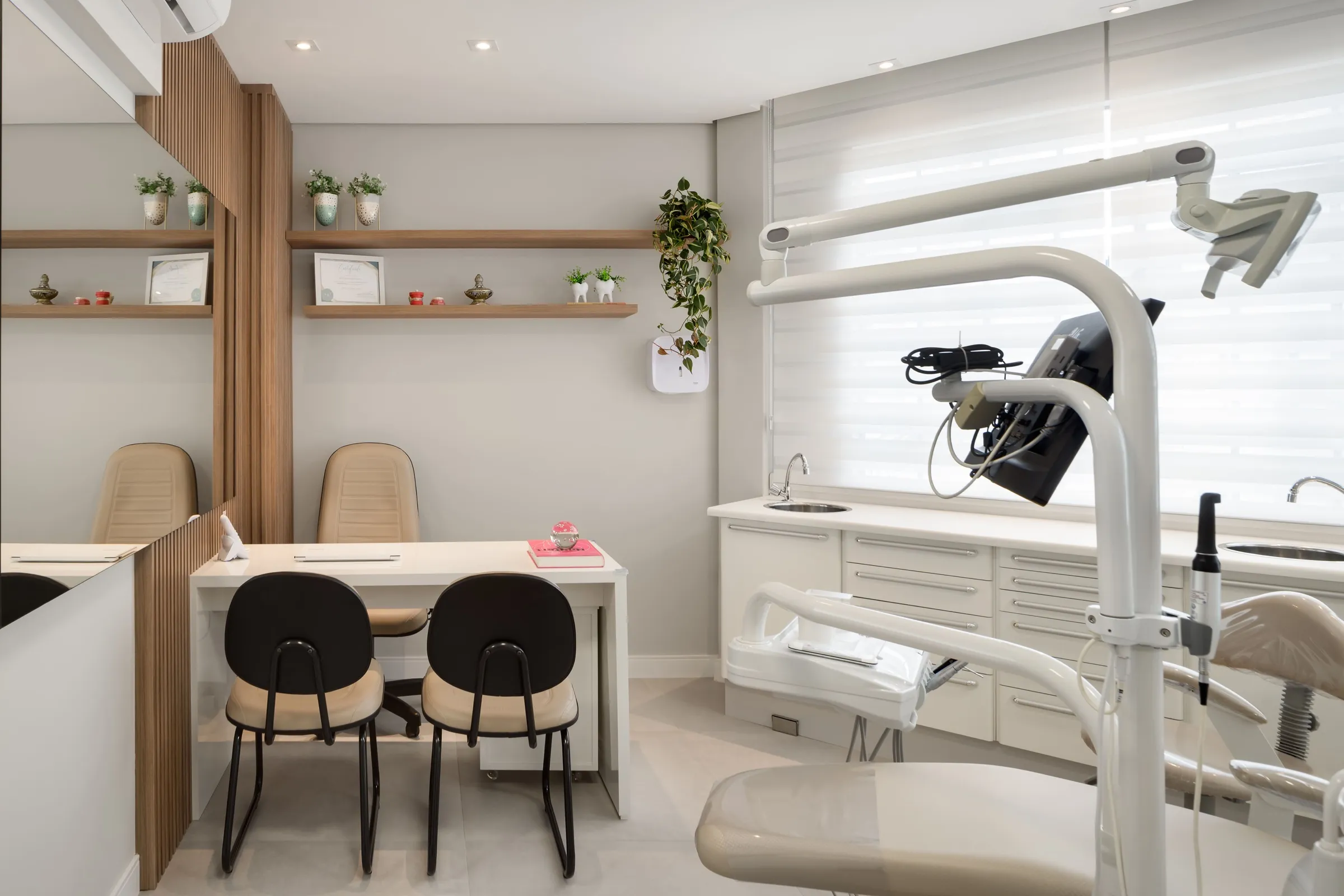 Sala de atendimento odontológico com cadeira, armário branco e mesa de apoio