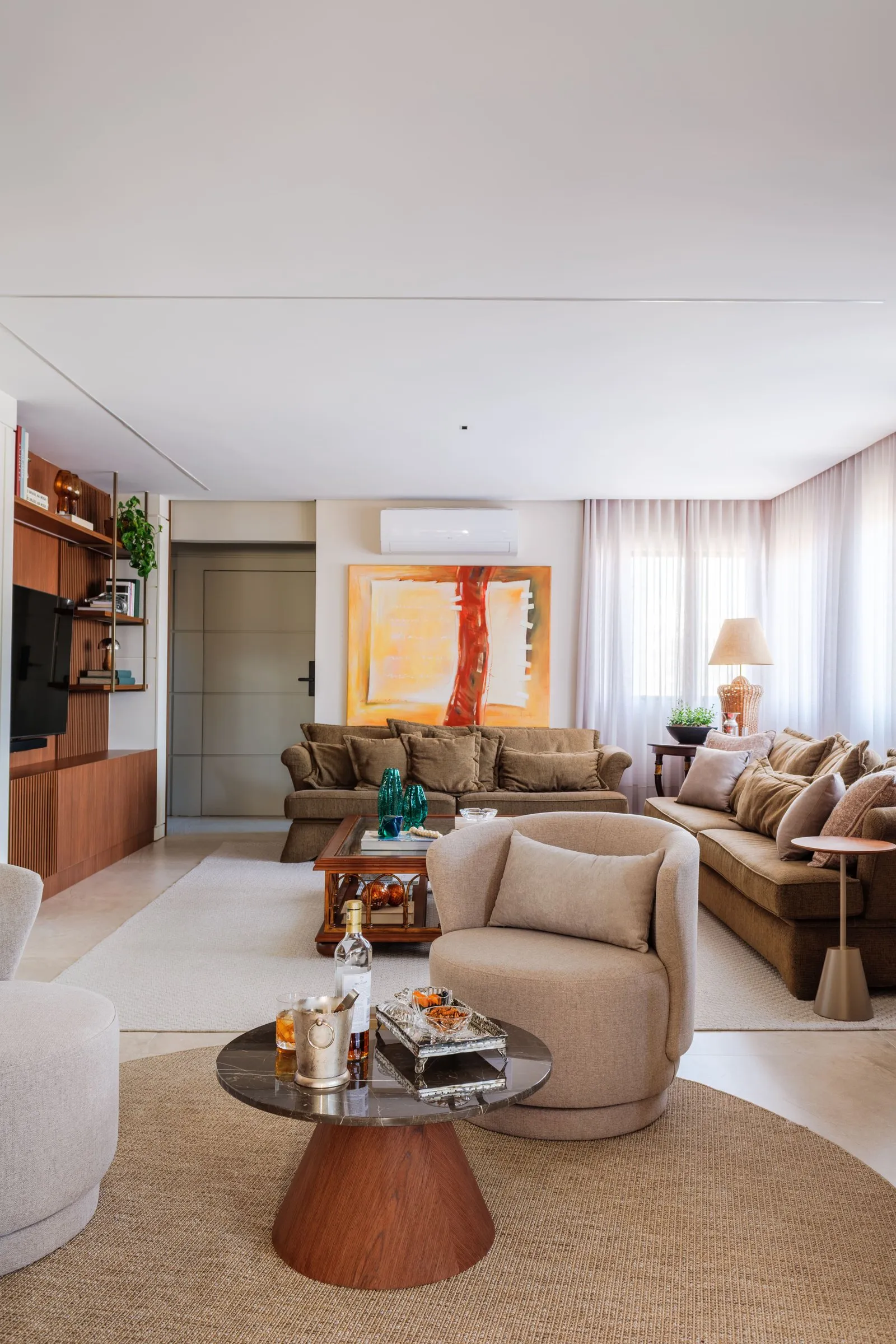Sala com poltrona redonda, tapete circular e sofás ao fundo