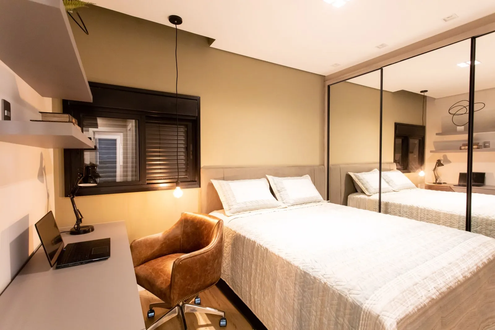Quarto com mesa de estudo, poltrona de couro e armário espelhado