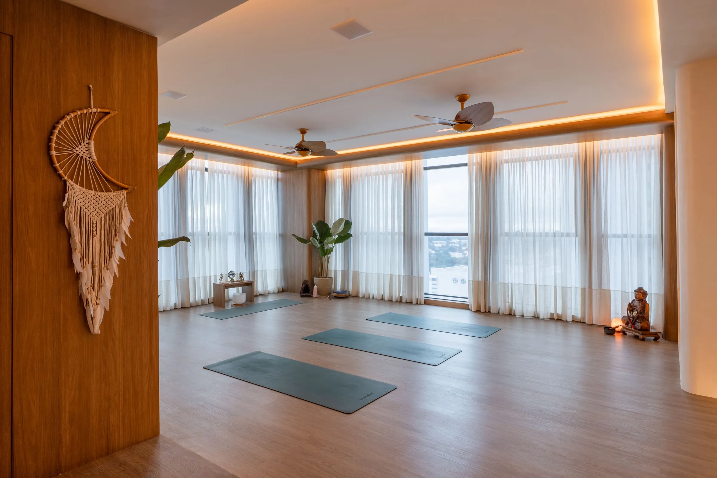 Sala de yoga vista da entrada com painel de madeira e filtro dos sonhos