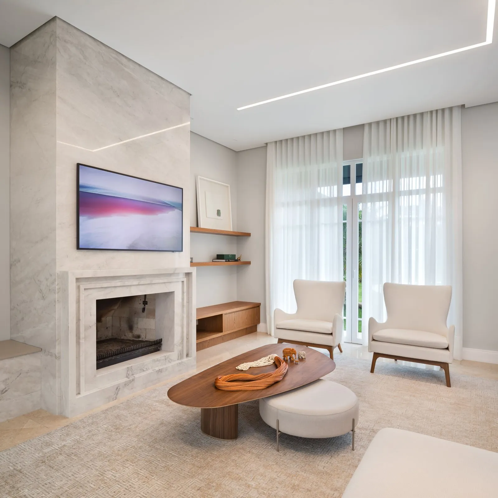 Sala com lareira de mármore, mesa de centro orgânica e cortinas longas