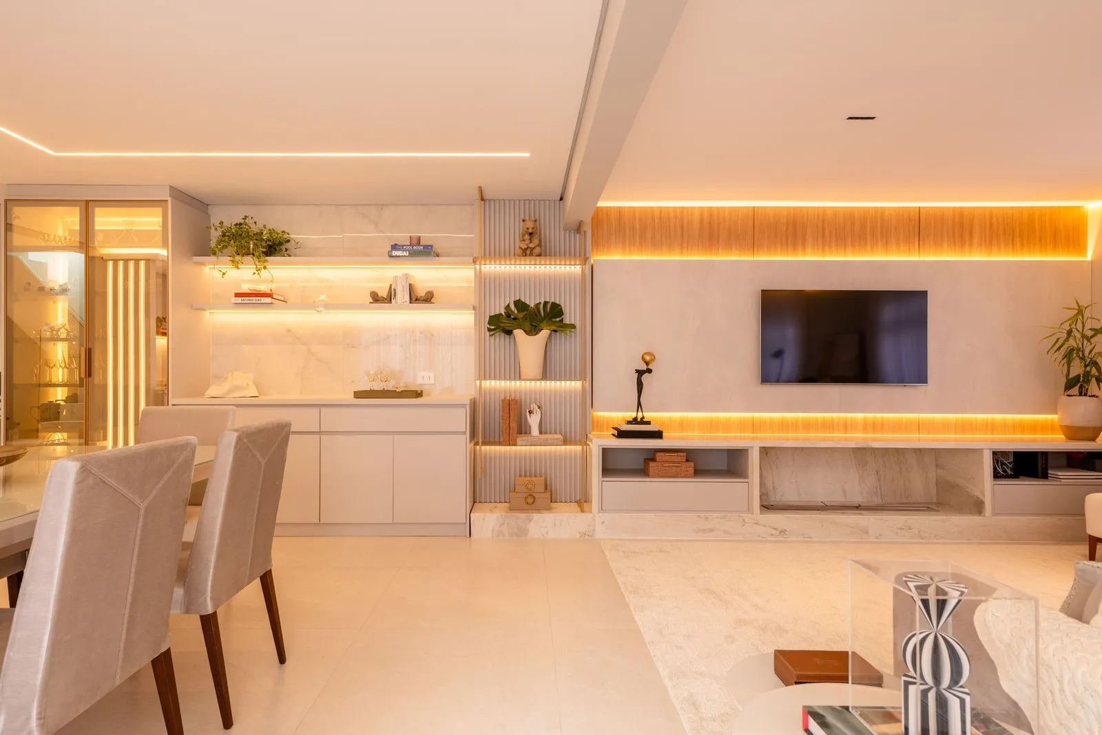 Sala de jantar e estar integradas com estante ripada e painel de TV iluminado