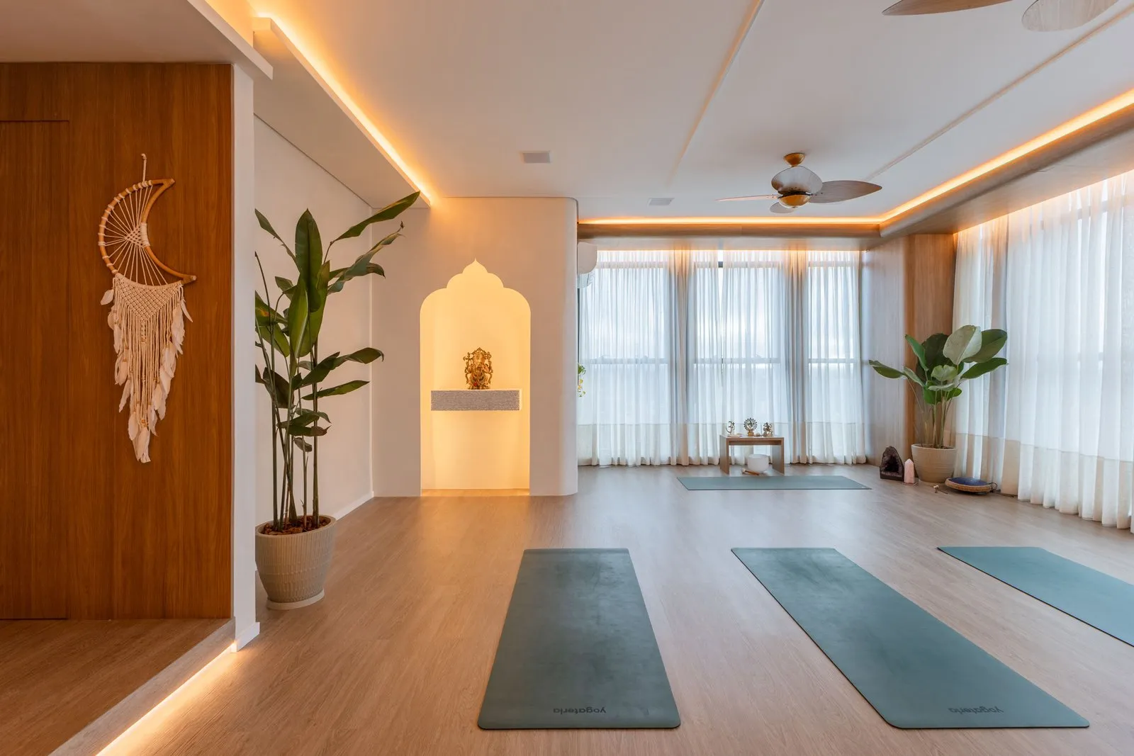 Sala de yoga com nicho em arco iluminado e painel de madeira à esquerda