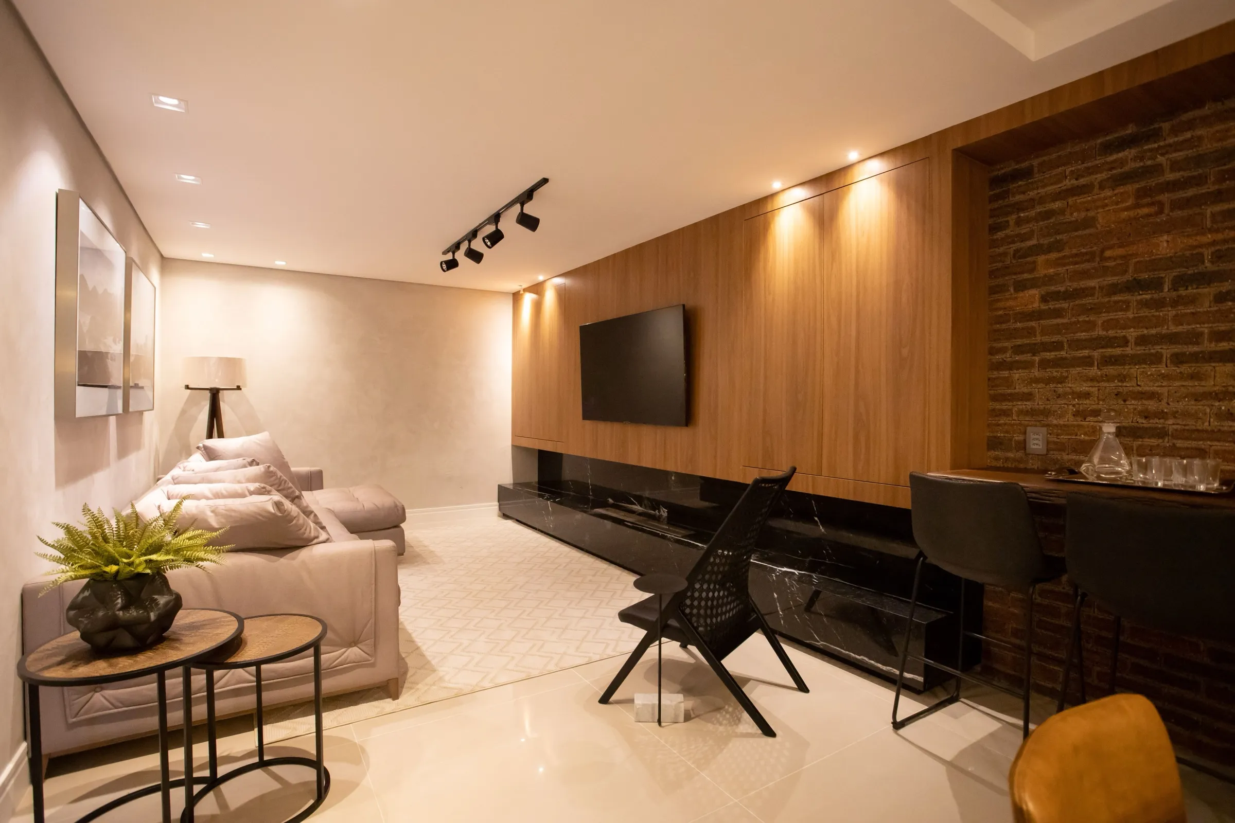 Sala de TV com painel de madeira, tijolinho e bancada de bar