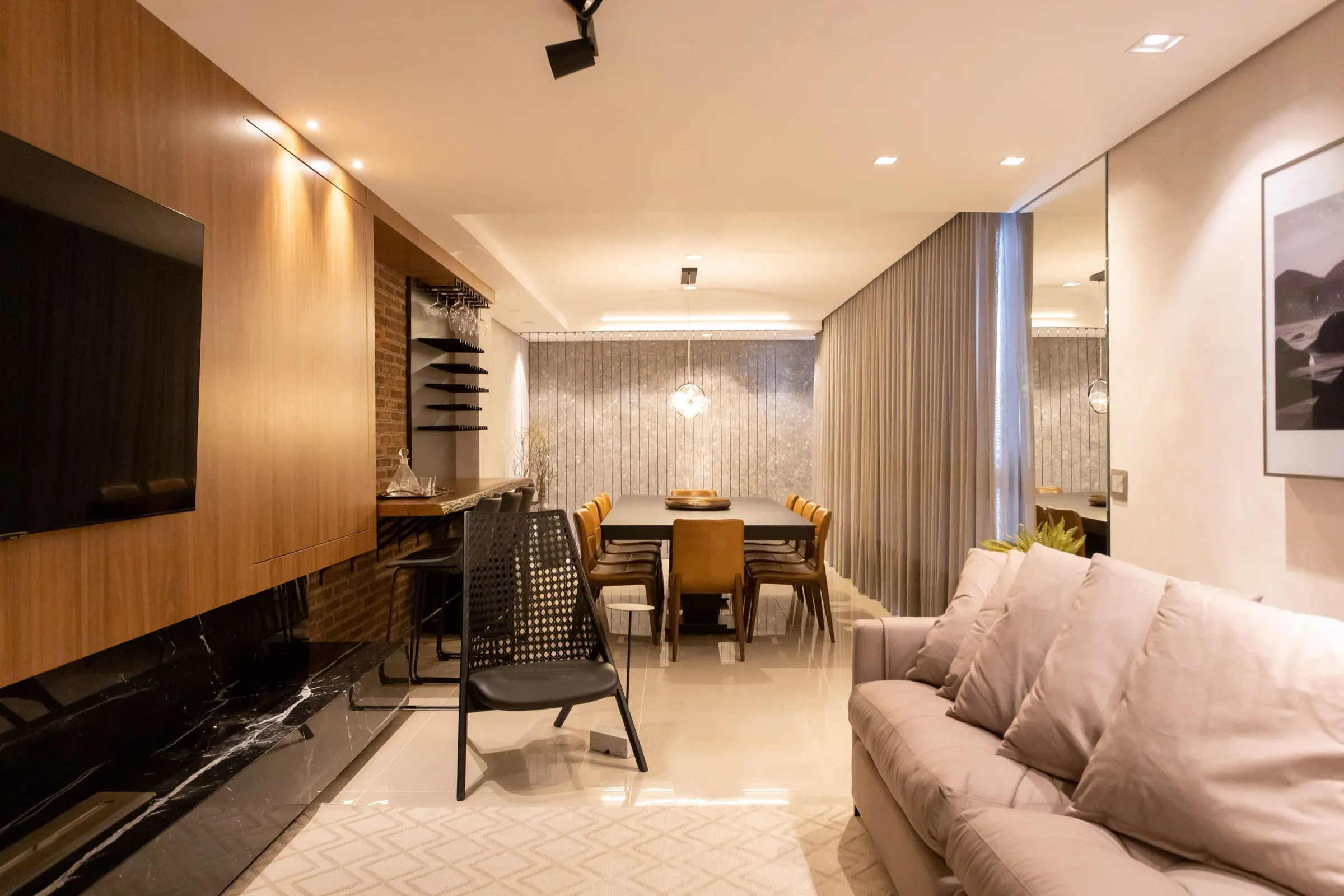Sala com rack em mármore preto, mesa de jantar ao fundo e cortina longa