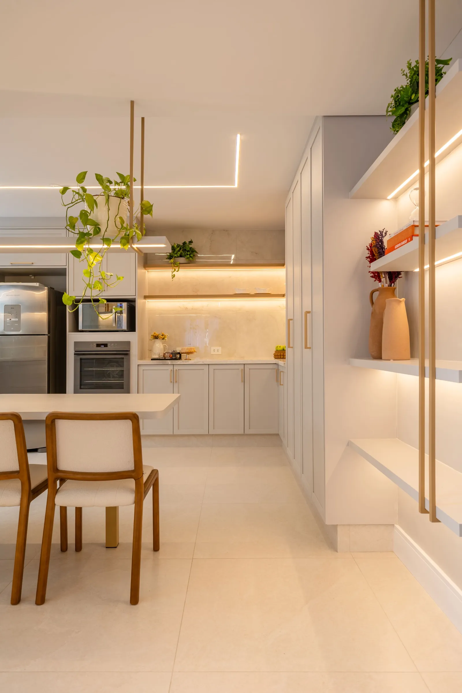 Cozinha com prateleiras suspensas iluminadas e mesa branca com cadeiras