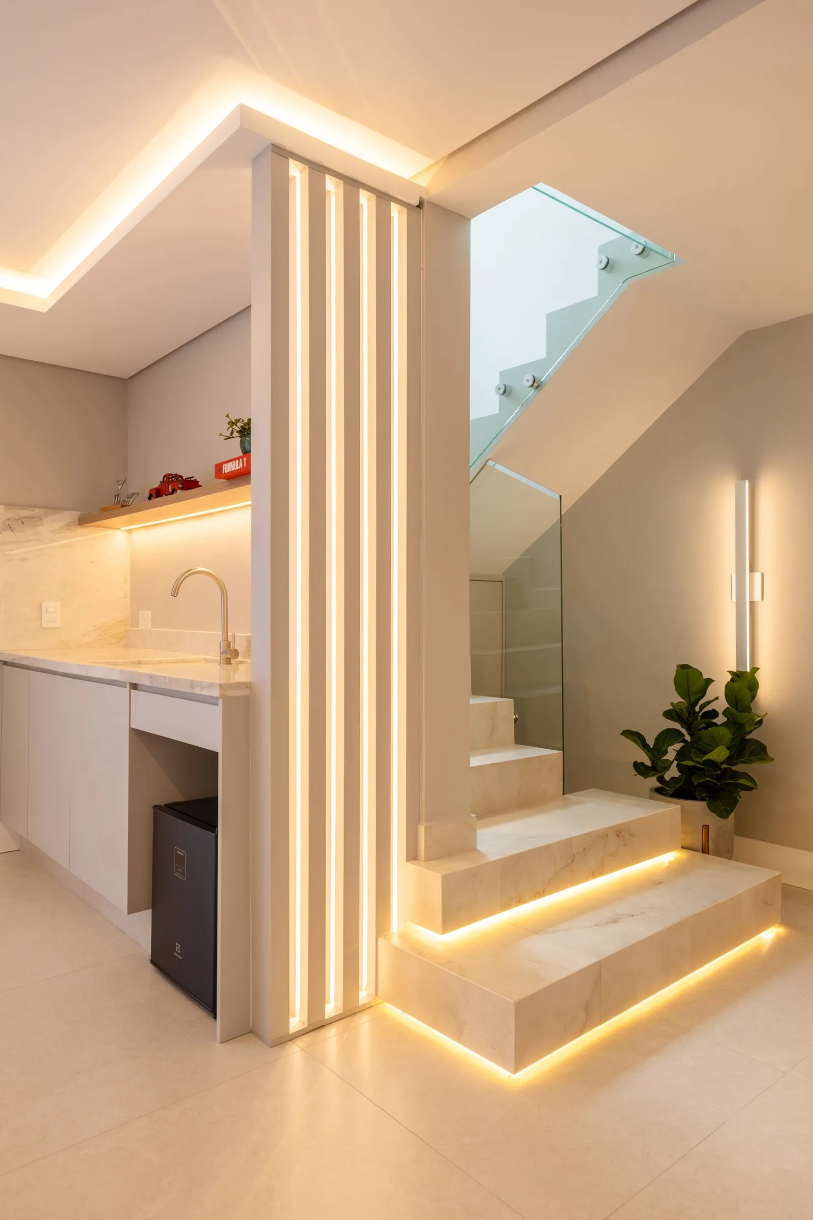 Escada de mármore iluminada ao lado de bancada com torneira e planta