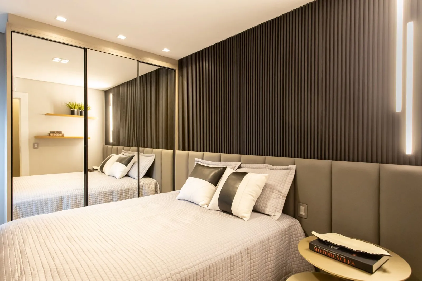 Quarto com painel ripado escuro, cabeceira estofada e armário espelhado