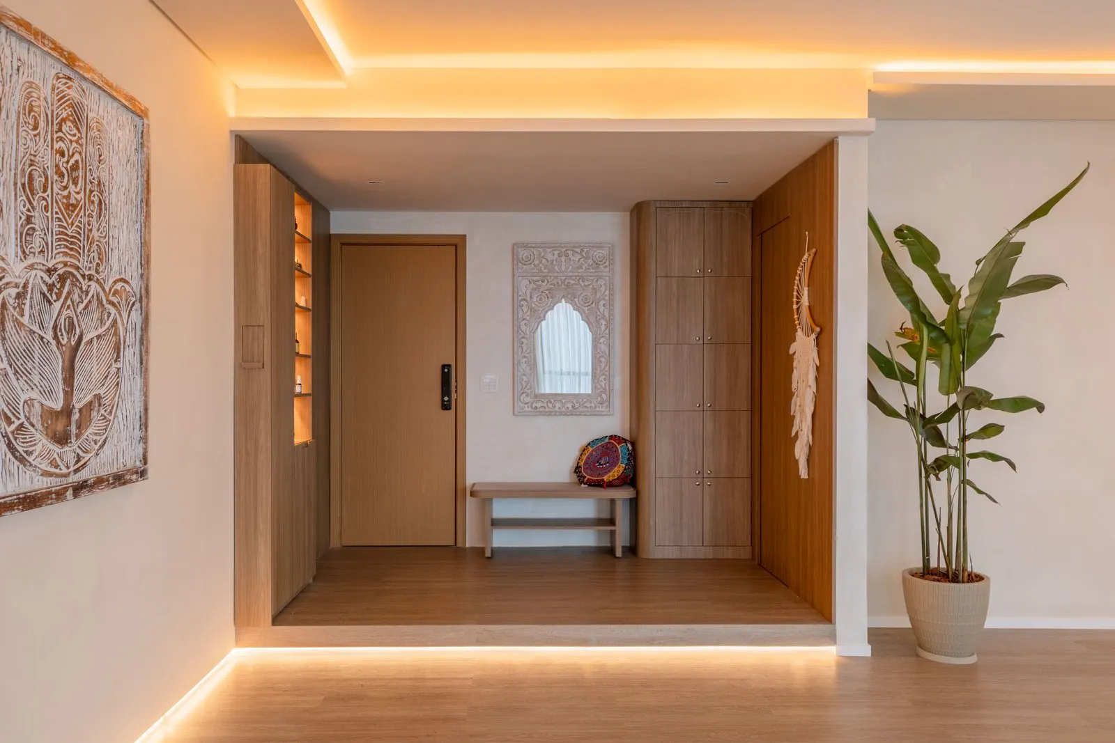 Hall de entrada com porta de madeira, armário, banco e espelho entalhado