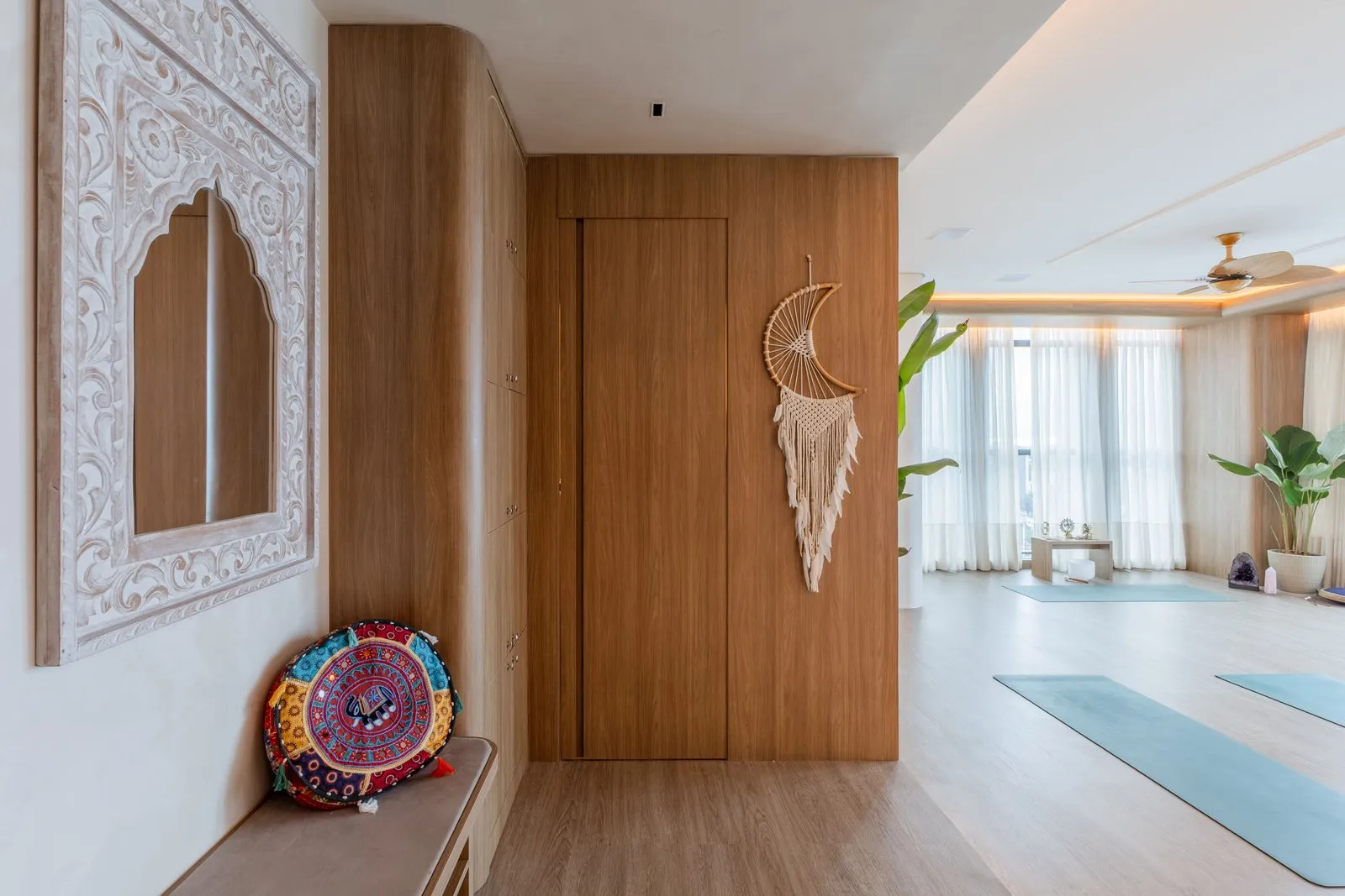 Banco com almofada colorida, espelho entalhado e vista da sala de yoga