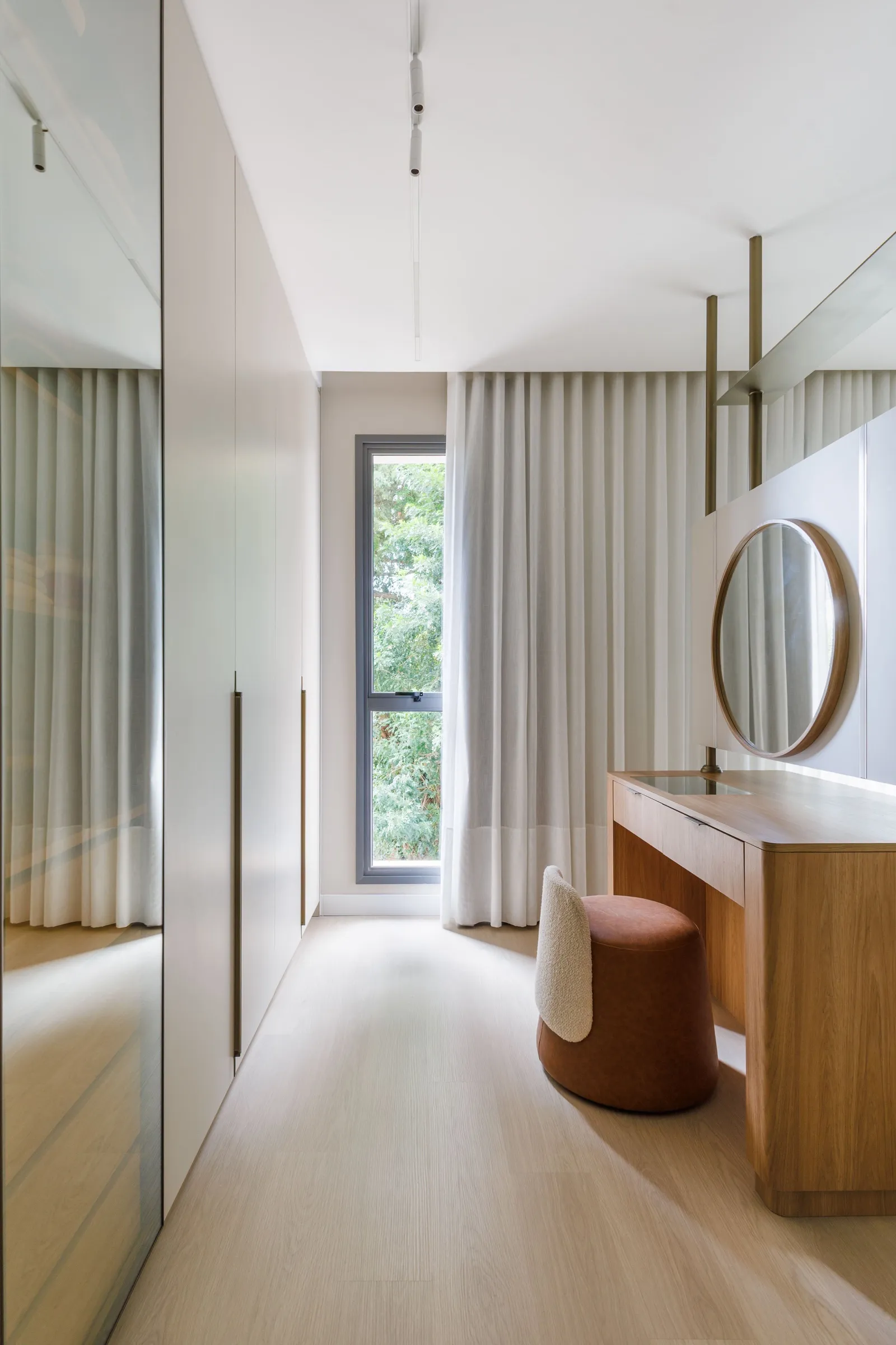 Closet com armários, janela com cortina e penteadeira com espelho redondo