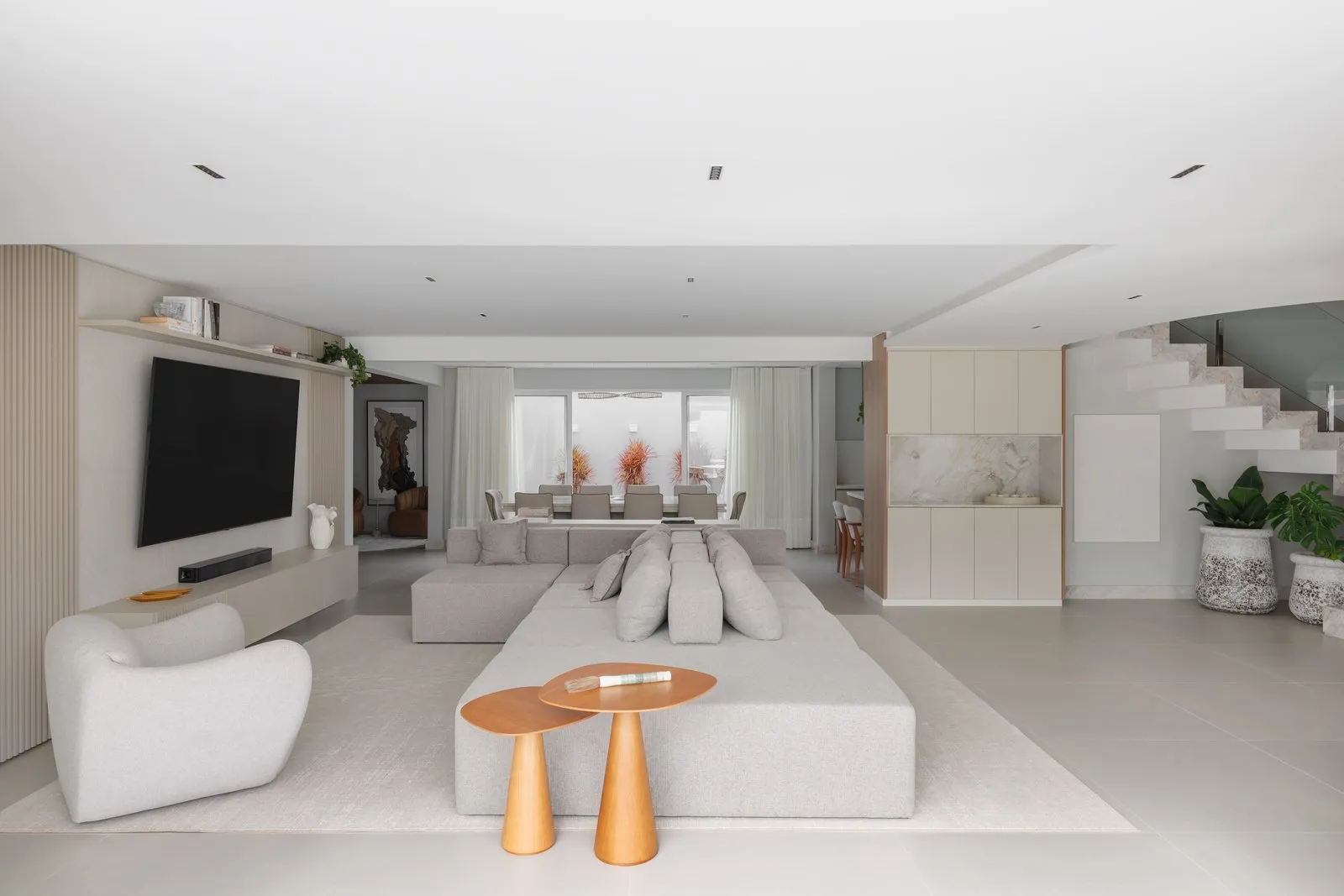Sala de estar e jantar integradas com sofá modular e escada ao fundo