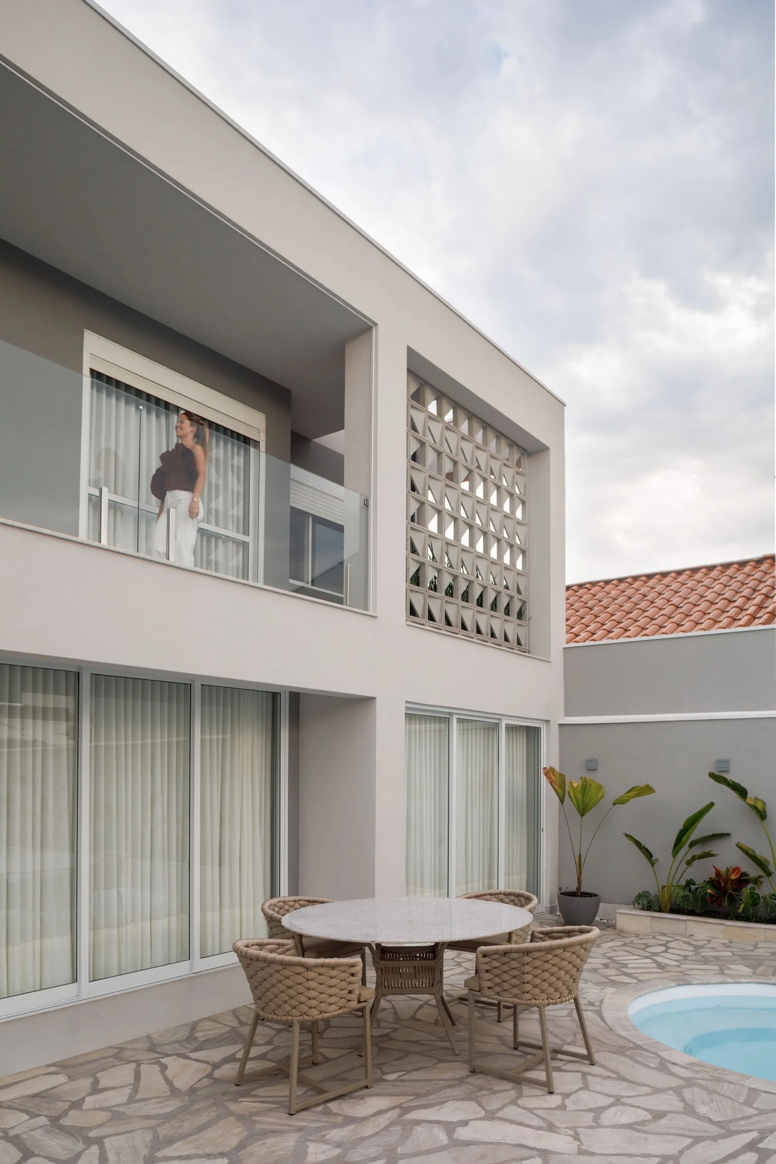 Fachada com cobogó e varanda, mesa de jardim e piscina no pátio