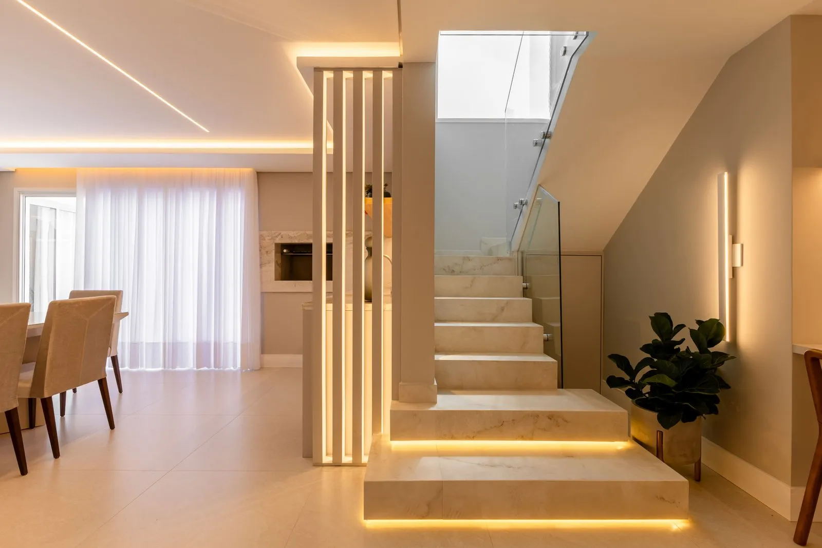 Escada de mármore com degraus iluminados por LED ao lado de um painel de ripas
