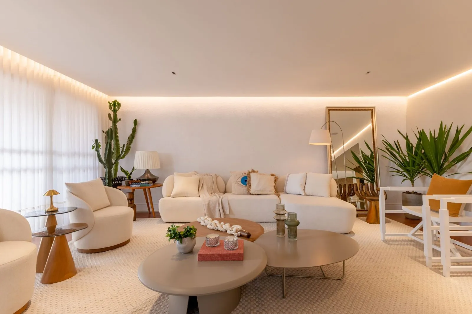 Sala de estar do Apartamento Grécia com sofá curvo e mesas de centro redondas