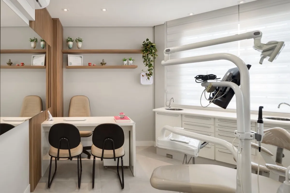 Consultório odontológico do projeto We Care, com cadeira de atendimento, bancada branca e mesa para conversar com o paciente