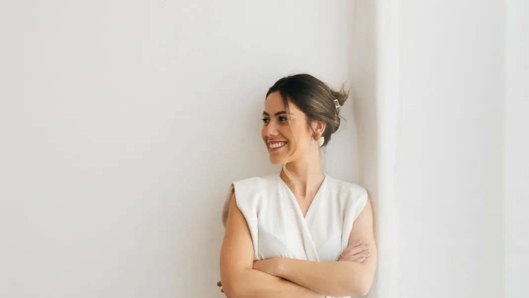 Rafaela Bender, arquiteta, encostada em uma parede clara